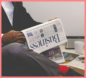 A person reading the Business section of a newspaper.