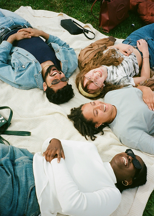 A group of friends lying on a blanket, laughing together.
